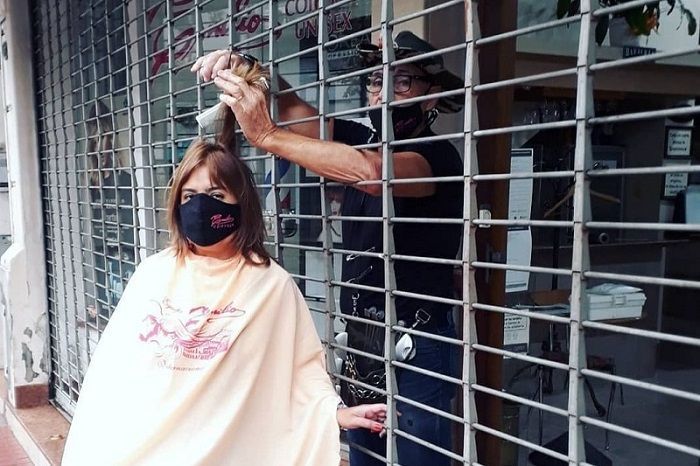 Dono de salão faz protesto contra lockdown cortando cabelo através de grade